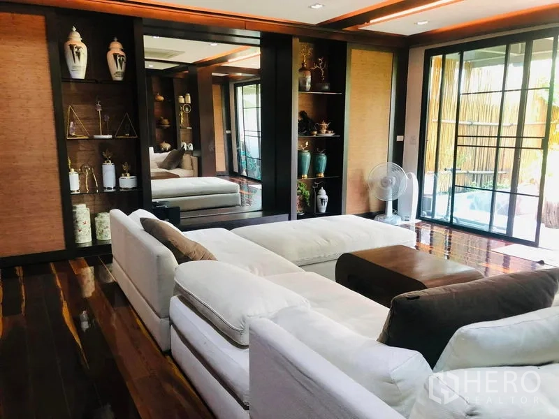 Townhouse for rent in Yan Nawa, Bangkok - Bright living room with sectional sofas opening to a terrace through sliding glass doors.