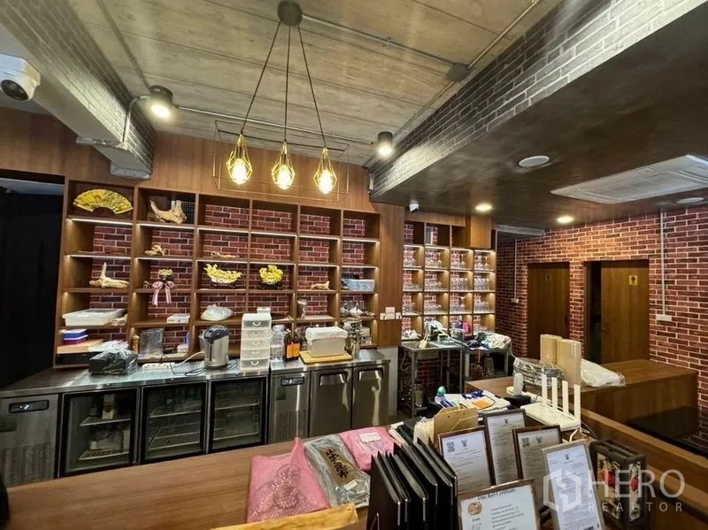 Shophouse for rent in Watthana, Bangkok - Front counter and display shelves under pendant lights in a restaurant-style shophouse.
