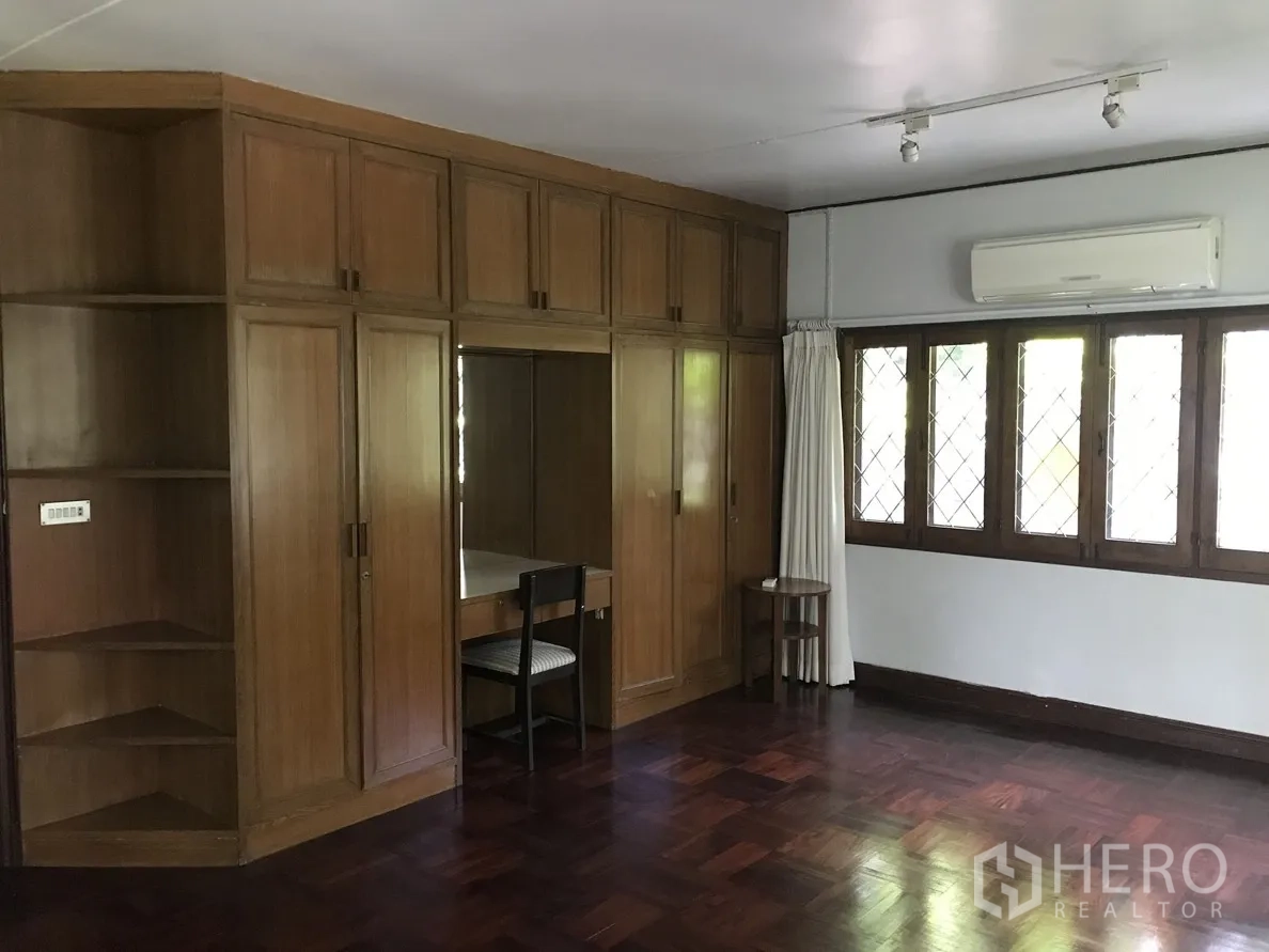独立式住宅 出租在Khlong Toei, Bangkok - 卧室带木质内置衣柜、拼花木地板和空调。