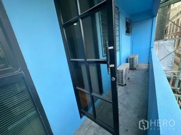 Office Space for rent in Bang Rak, Bangkok - Narrow balcony with blue walls, black-framed glass door and outdoor AC units overlooking the city.