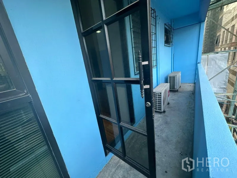Office Space for rent in Bang Rak, Bangkok - Narrow balcony with blue walls, black-framed glass door and outdoor AC units overlooking the city.