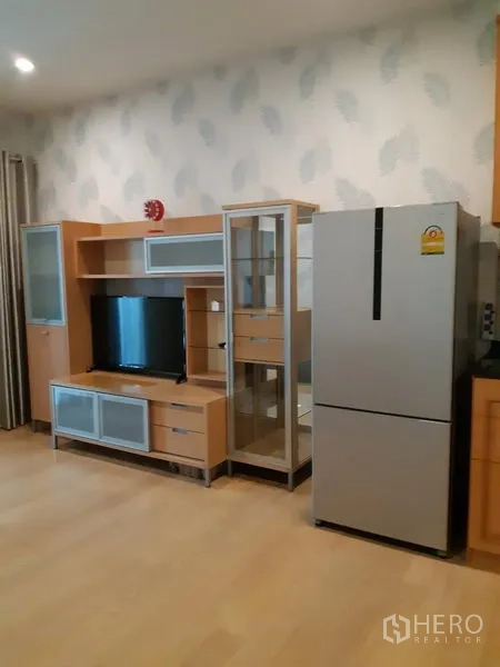 Condominium for rent in Phaya Thai, Bangkok - Living room with wood-toned TV cabinet, glass display unit, and a stainless refrigerator.