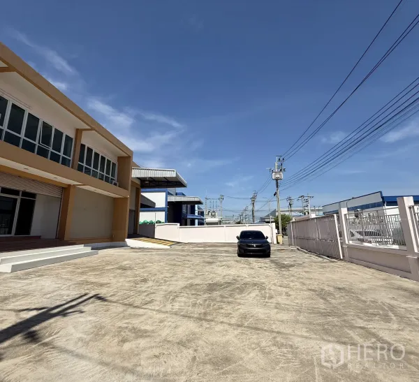 Warehouse for rent or sale in Bang Bo, Samut Prakan - Gated concrete forecourt with two‑storey office and warehouse building, ample driveway for trucks.