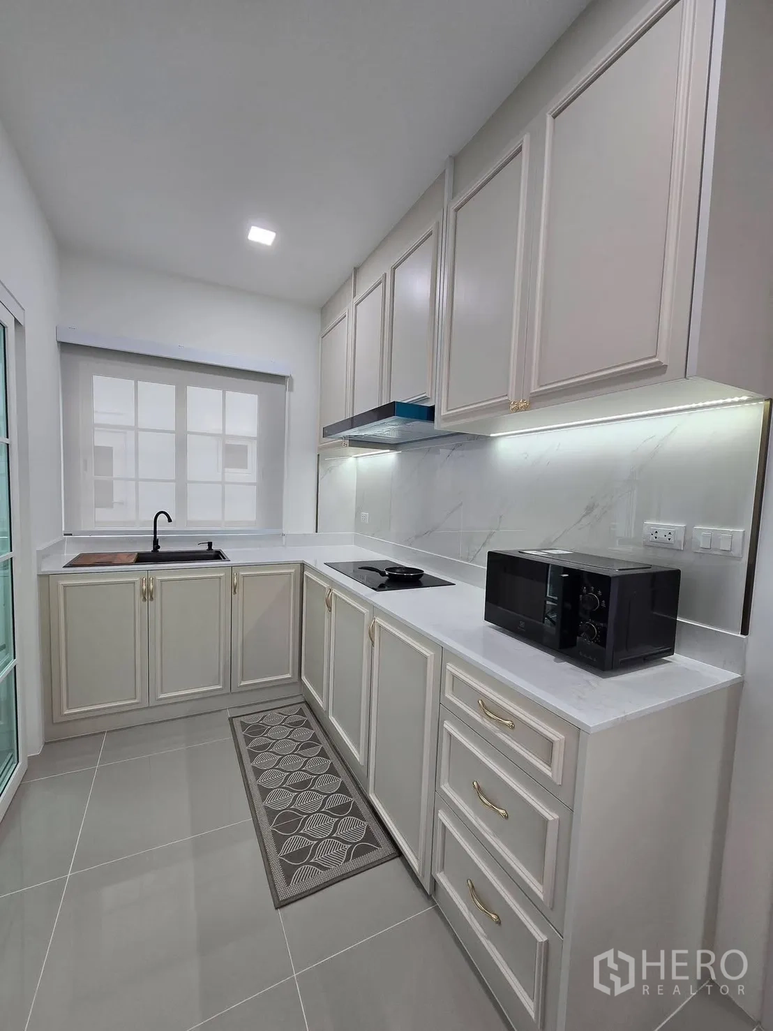 Semi-detached House for rent in Mueang Samut Prakan, Samut Prakan - Kitchen angle with sink, cooktop, microwave and ample storage space.