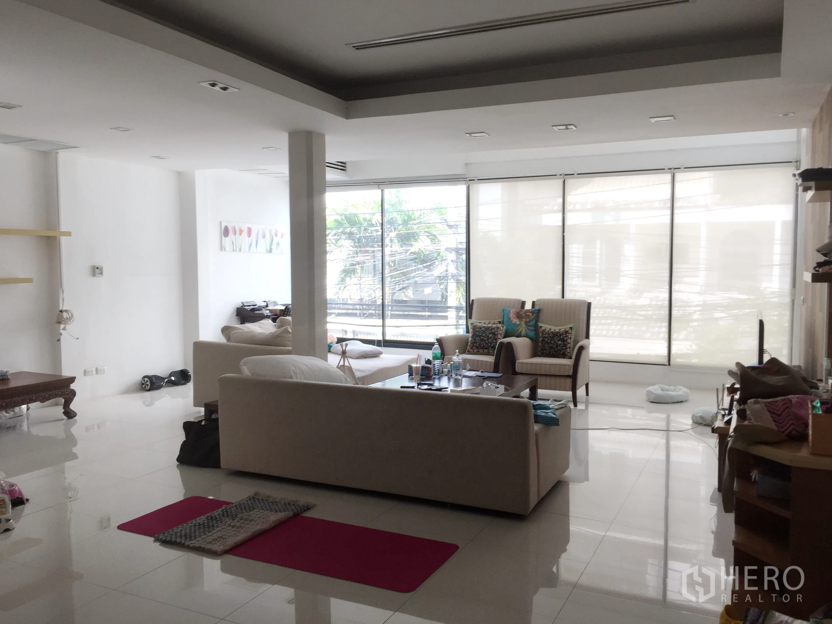 联排别墅 出租在Khlong Toei, Bangkok - 宽阔起居区，白色抛光地砖与大扇推拉窗，引入充足自然光。