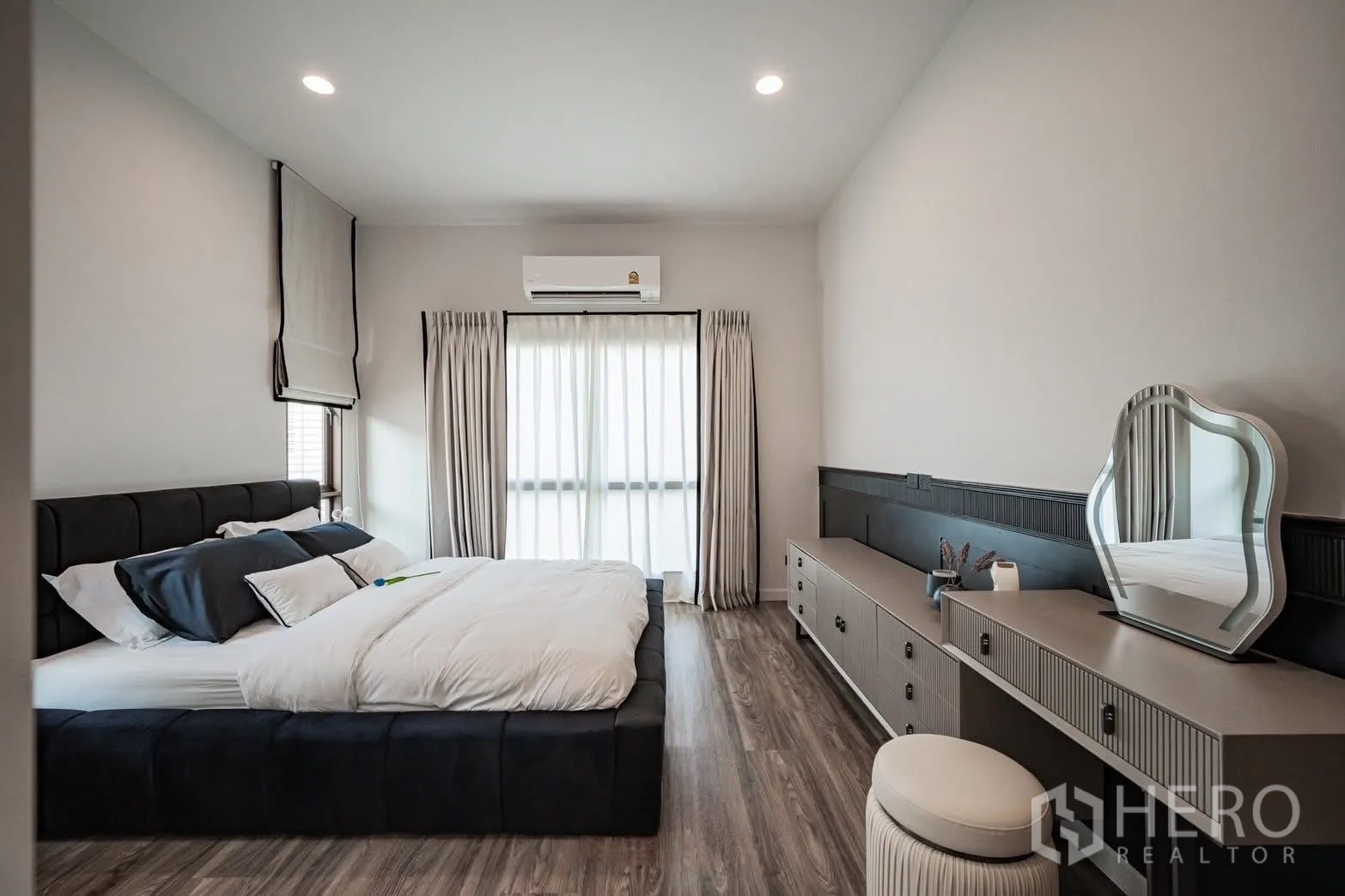 Detached House for sale in Bang Kapi, Bangkok - Spacious bedroom with low platform bed, long built-in dressing table, large window and wood floors.