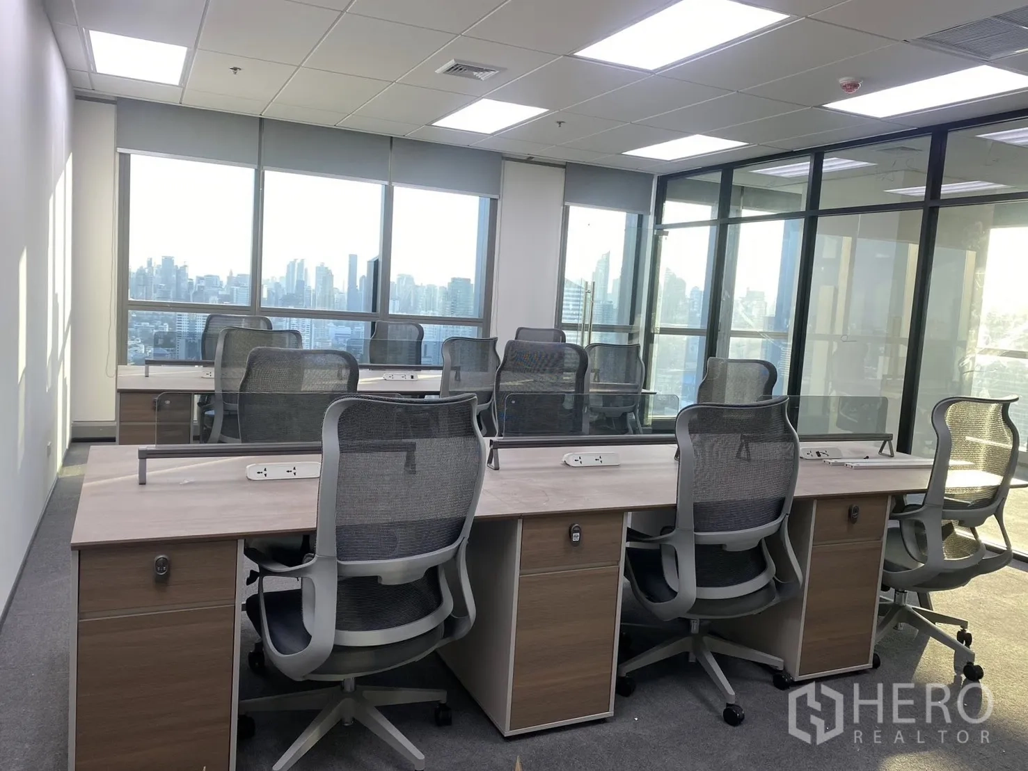 Office Space for rent in Huai Khwang, Bangkok - Bench desks with mesh chairs, power outlets and large windows overlooking the skyline.