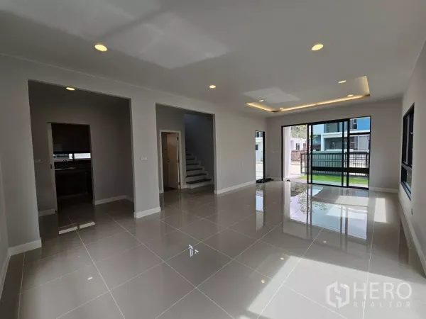 Detached House for sale in Lam Luk Ka, Pathum Thani - Bright open-plan living area with large sliding glass doors and glossy tiled floors.