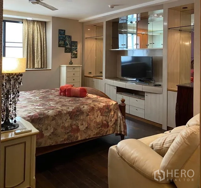 Condominium for rent in Khlong Toei, Bangkok - Master bedroom with floral bedding, built-in wardrobes and TV unit at President Park condo in Khlong Toei, Bangkok.