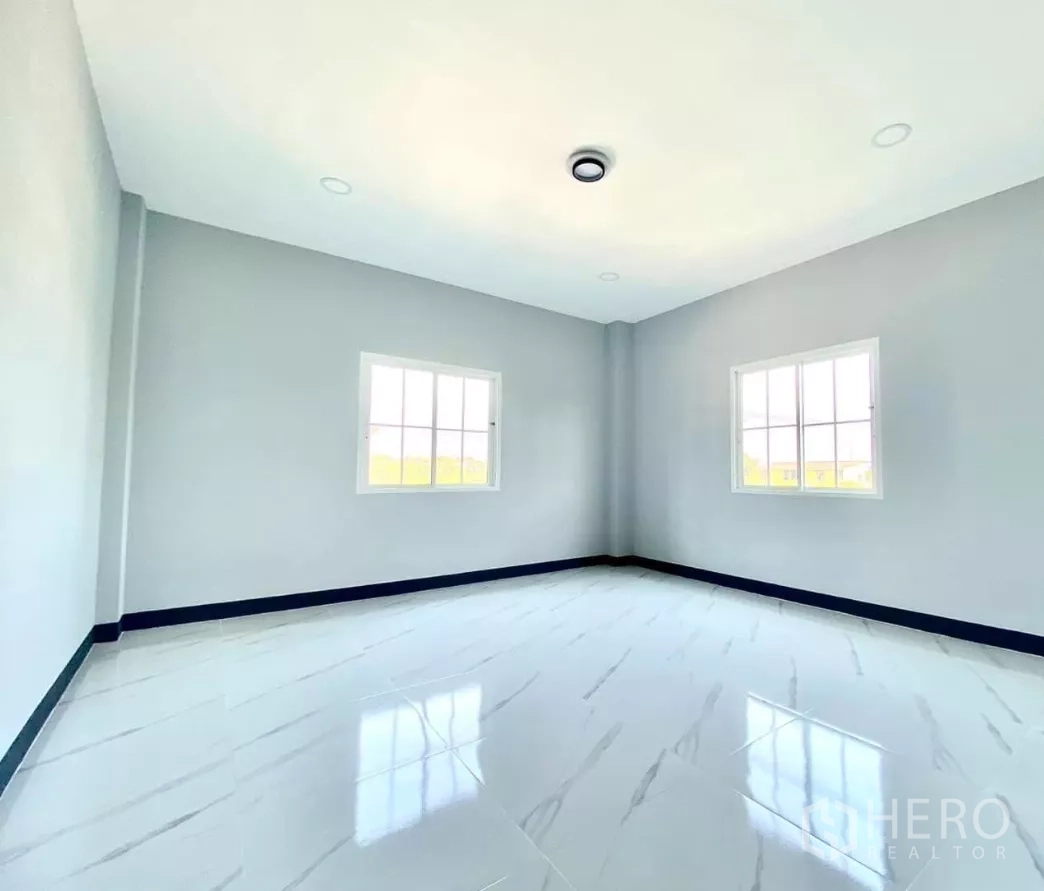 Factory for rent or sale in Bang Bua Thong, Nonthaburi - Bright bedroom with two windows and marble-look floor tiles.