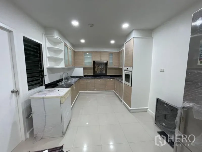 公寓 出租在Khlong Toei, Bangkok - 独立U型厨房，浅木橱柜，黑色台面与嵌入式烤箱