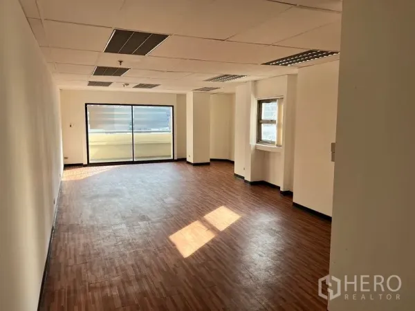 Office Space for rent in Pathum Wan, Bangkok - Bright open-plan office with wood-look flooring, drop ceiling lighting, and large sliding glass doors to a balcony.