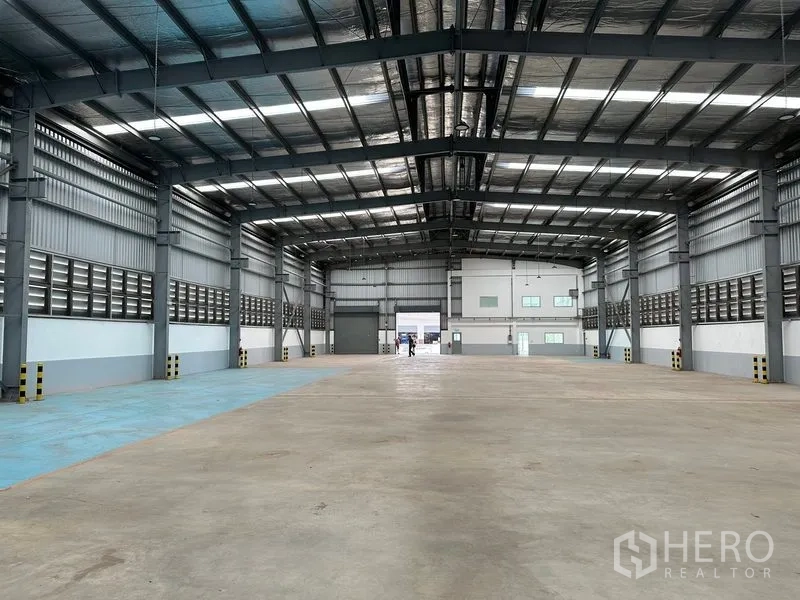 Factory for rent in Mueang Samut Prakan, Samut Prakan - Warehouse interior facing rear office block with dual roller shutters and ample lighting.