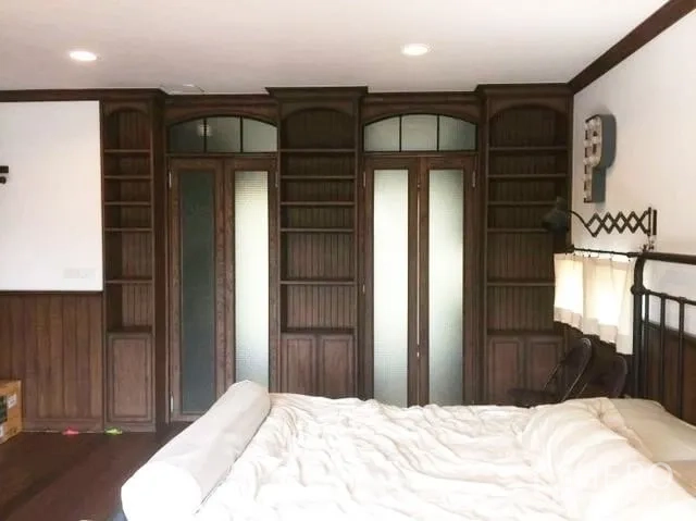 Townhouse for sale in Suan Luang, Bangkok - Master bedroom wall featuring arched wooden wardrobes and frosted-glass doors.