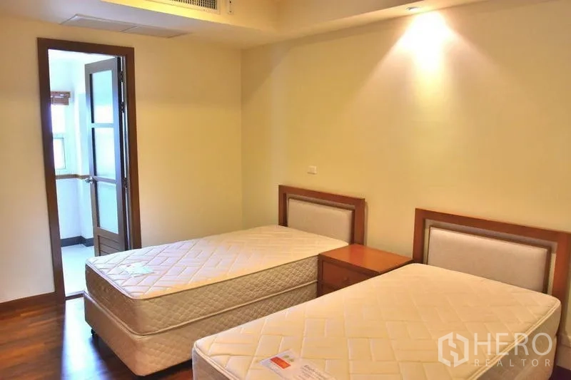 Apartment for rent in Sathon, Bangkok - Guest bedroom with twin single beds and warm lighting.