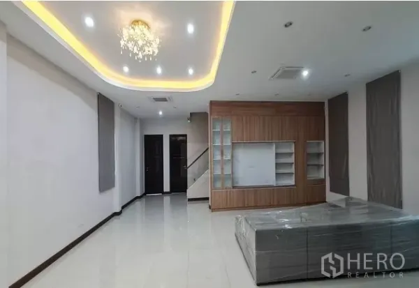 带办公室的家 出租在Watthana, Bangkok - 明亮客厅，灯带吊顶与水晶灯，亮面瓷砖地面，内置柜及后方楼梯