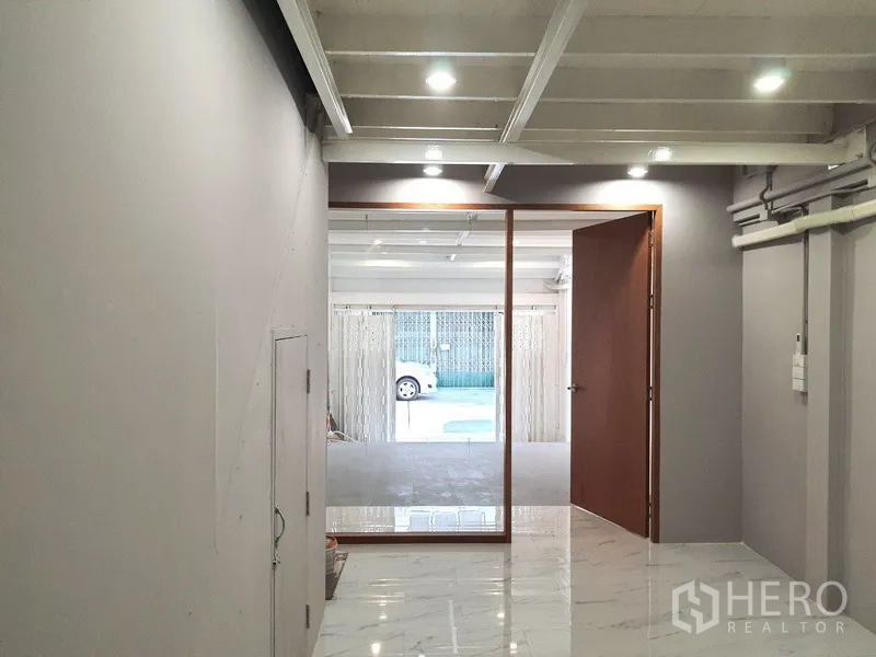 Shophouse for rent in Phra Khanong, Bangkok - View from an inner room through a glass partition toward the front parking area and street.