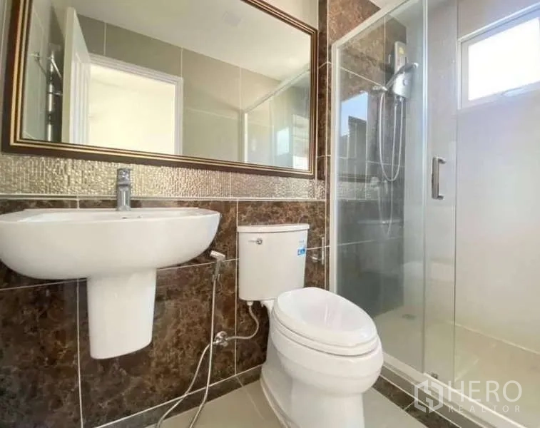 Detached House for sale in Bang Khen, Bangkok - Modern bathroom with glass-enclosed shower, pedestal sink, toilet and large mirror.