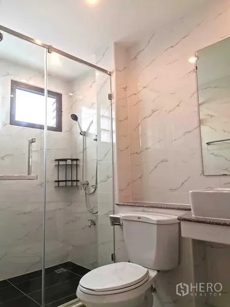 独立式住宅 出租在Bang Rak, Bangkok - 浴室配玻璃淋浴房、坐厕与仿石纹瓷砖，干净现代。