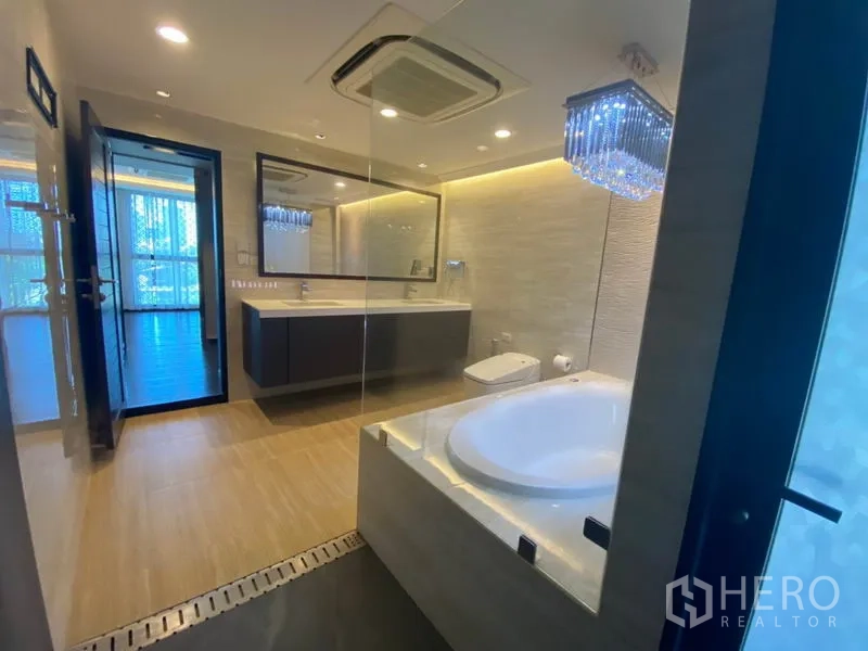 Townhouse for sale in Yan Nawa, Bangkok - Spacious contemporary bathroom featuring a round soaking tub, chandelier, floating vanity and glass partition.