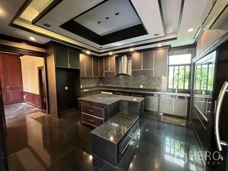 Detached House for sale in Lam Luk Ka, Pathum Thani - Modern U‑shaped kitchen with island, dark cabinetry and mosaic backsplash