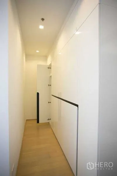 Condominium for rent in Watthana, Bangkok - Corridor with floor-to-ceiling built-in storage cabinets in glossy white.