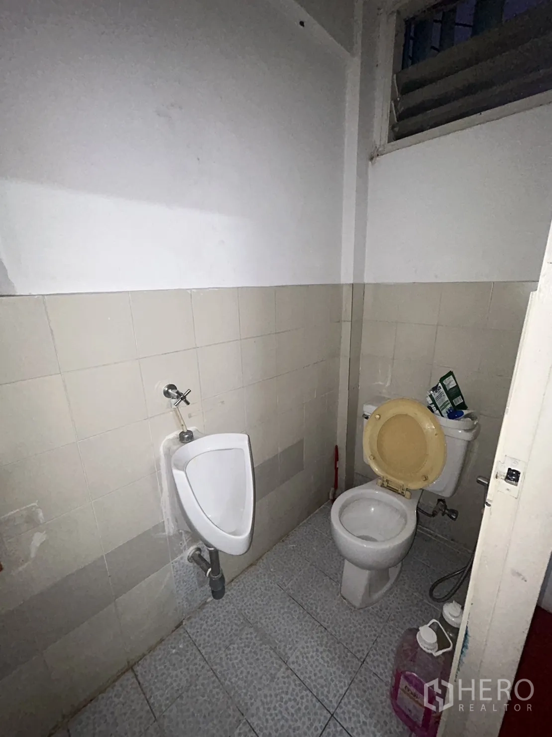 Shophouse for rent in Khlong Toei, Bangkok - Older restroom with urinal and toilet on tiled flooring.