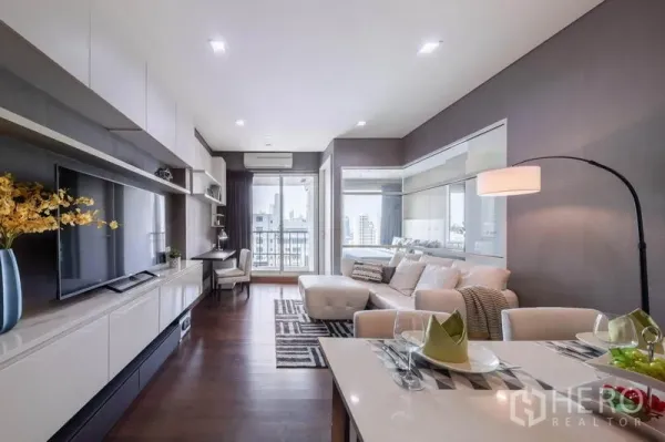 Condominium for rent in Watthana, Bangkok - Bright lounge with TV wall, balcony access, and skyline outlook.