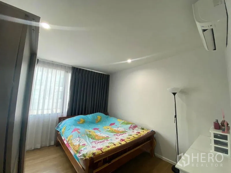 Townhouse for rent or sale in Saphan Sung, Bangkok - Secondary bedroom with double bed, window drapes and a wall-mounted air conditioner.