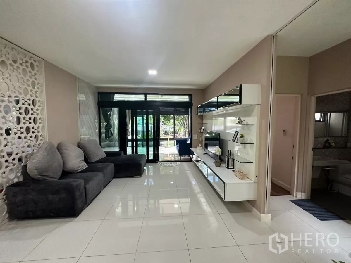 Detached House for rent or sale in Bang Kapi, Bangkok - Lounge facing glass doors with floating shelving, adjacent to a bathroom entrance.