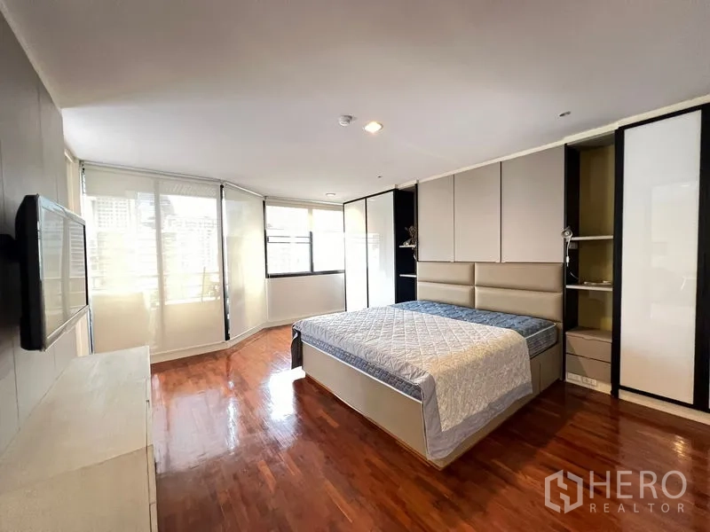 Condominium for rent or sale in Khlong Toei, Bangkok - Corner master bedroom with large windows, built-in wardrobes and wood flooring.