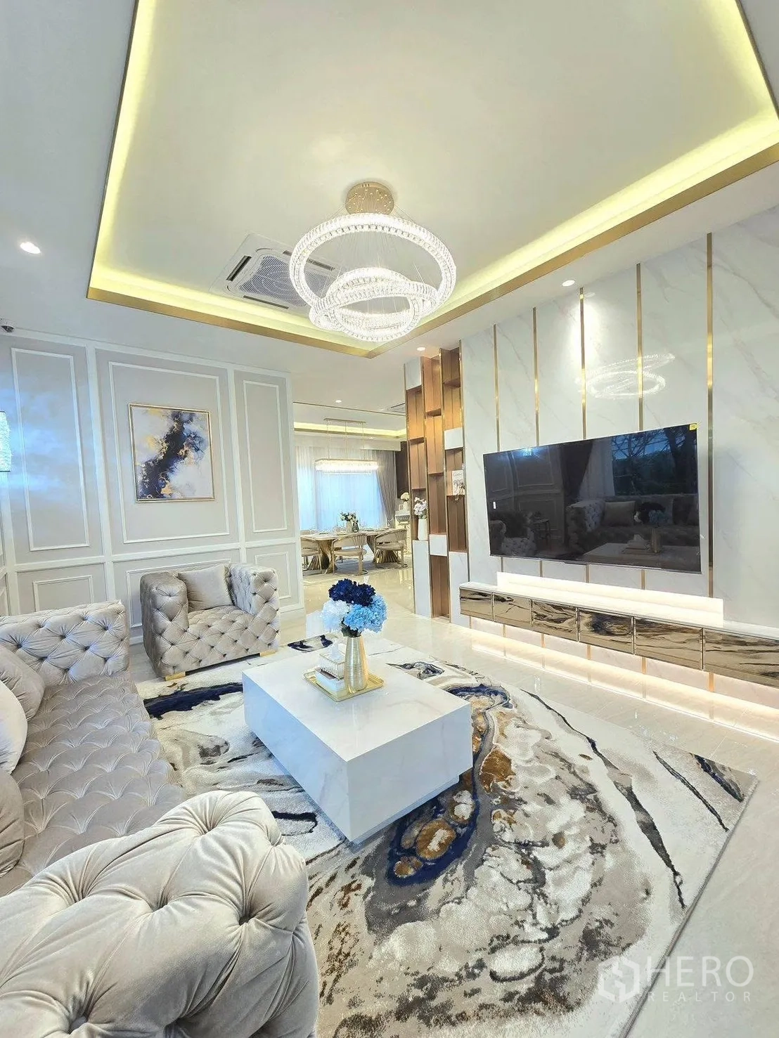 บ้านเดี่ยว for rent or sale in Bang Phli, Samut Prakan - มุมห้องนั่งเล่นเชื่อมโต๊ะทานอาหาร เคาน์เตอร์ทีวีหินอ่อน พรมลายศิลป์ และฝ้าเพดานดีไซน์