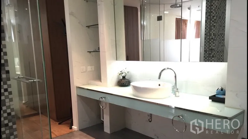 Condominium for rent in Bang Rak, Bangkok - Vanity with vessel sink, large mirror and glass shower in a contemporary bathroom.