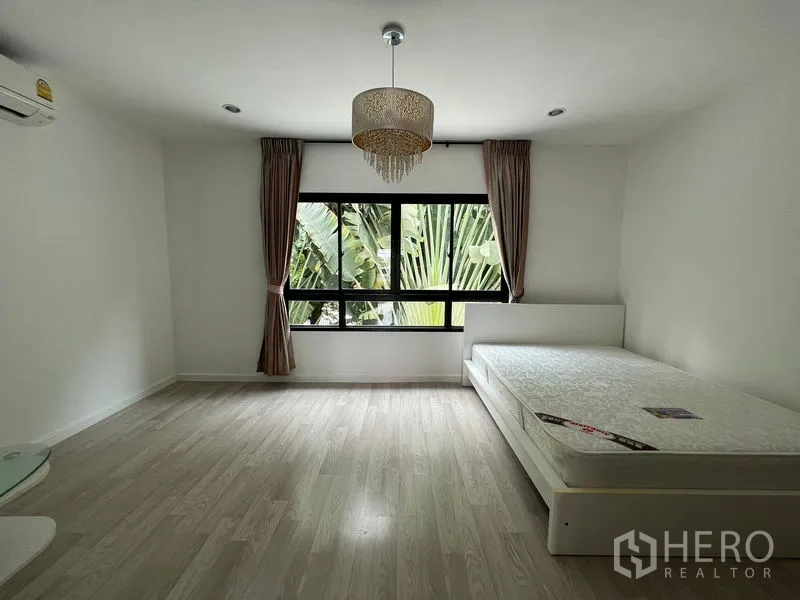 Townhouse for sale in Bang Kapi, Bangkok - Bedroom with bed and chandelier, big window offering garden views.