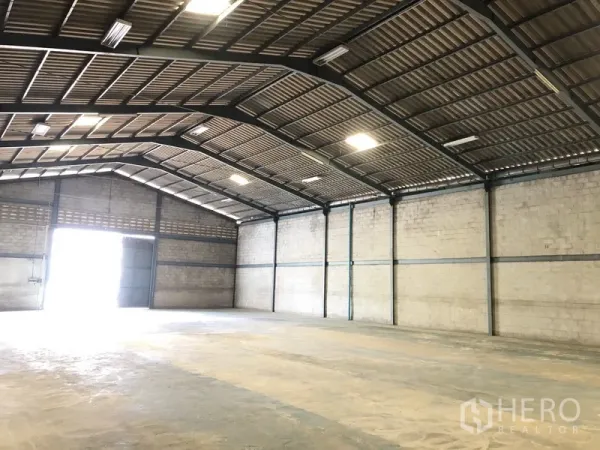 货栈 出租在Khlong Luang, Pathum Thani - 明亮的仓库内部，高挑人字顶、通风砖墙体与大型出入口。