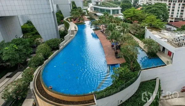 Condominium for rent or sale in Khlong Toei, Bangkok - Resort-style condominium swimming pool with wooden sundeck, palm trees and landscaped gardens.