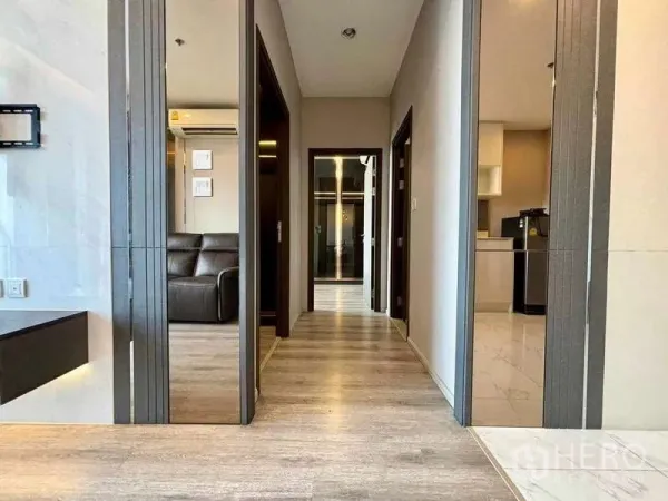 Condominium for rent or sale in Bang Na, Bangkok - Bright corridor with wood flooring leading to bedrooms and kitchen in a modern condo.
