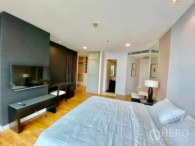 Condominium for rent or sale in Sathon, Bangkok - Bedroom with TV on feature wall, writing desk, and sliding door to closet.