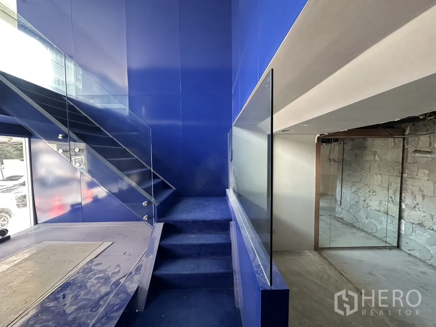 พื้นที่ขายของ for rent in Watthana, Bangkok - บันไดไฮไลต์สีน้ำเงินพร้อมราวกระจกและพื้นที่ดิสเพลย์ริมหน้าต่าง.
