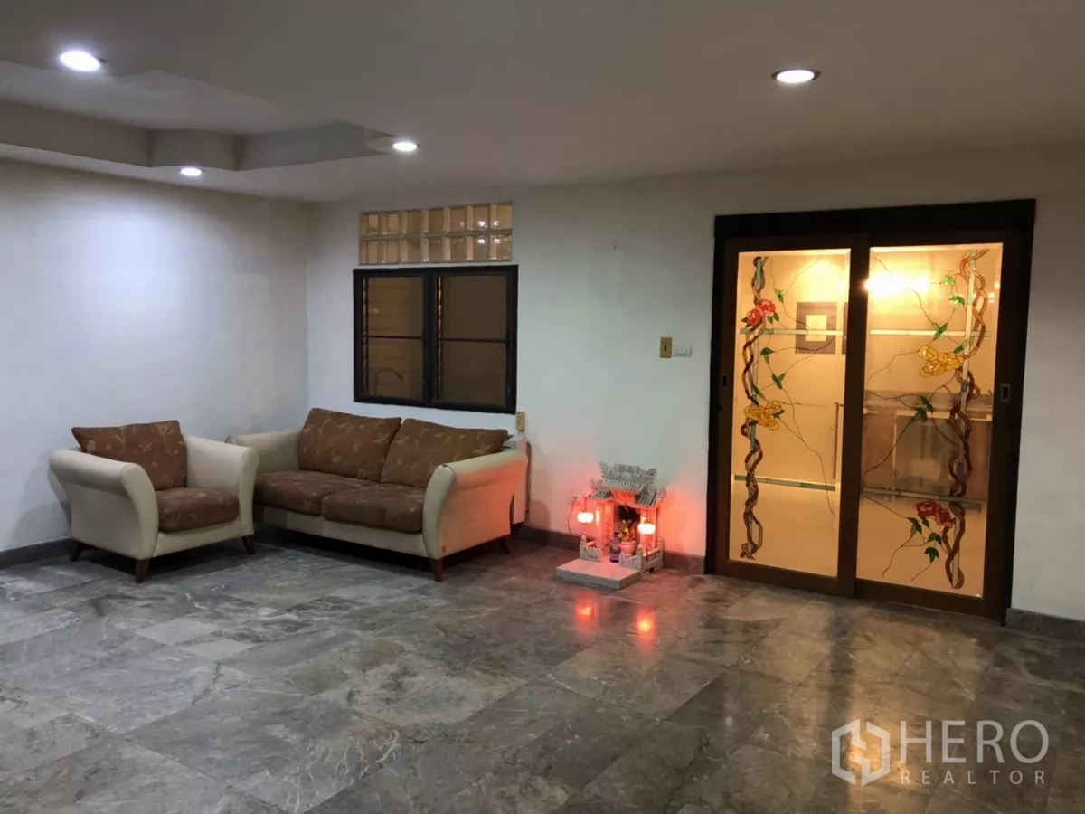 สำนักงานที่บ้าน ให้เช่าในPhra Khanong, Bangkok - พื้นที่นั่งเล่นกว้าง โซฟา ไฟดาวน์ไลท์ พื้นหิน และประตูบานเลื่อนกระจกลายดอกไม้