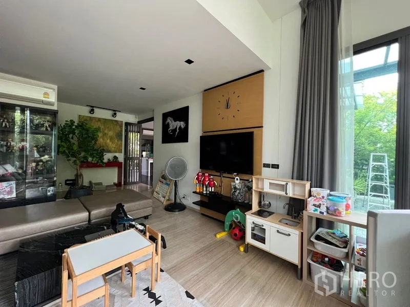 Detached House for sale in Bang Kapi, Bangkok - Entertainment wall with mounted TV, storage and windows to the garden.