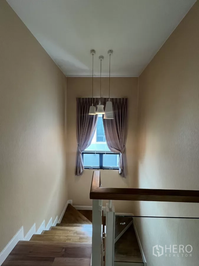 Detached House for rent in Bang Kapi, Bangkok - Stairwell with wooden handrail, pendant lights, and curtained window.