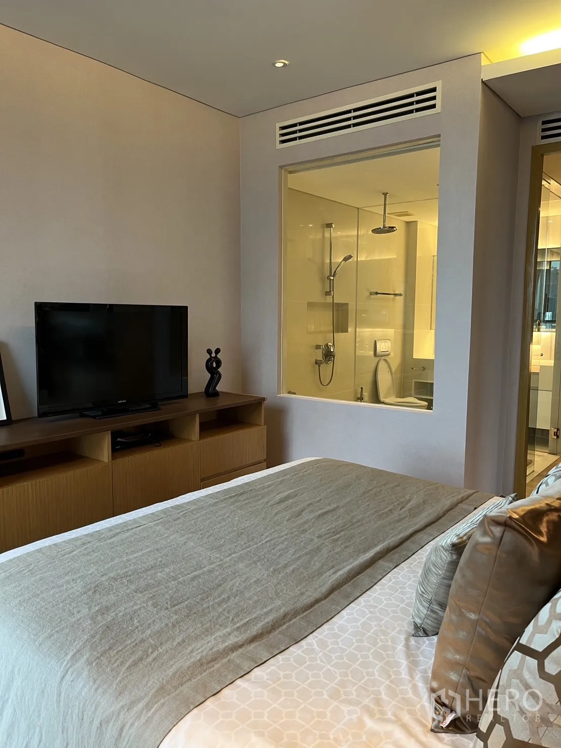 Condominium for rent in Watthana, Bangkok - Bedroom angle with TV cabinet and glass window to the ensuite bathroom.