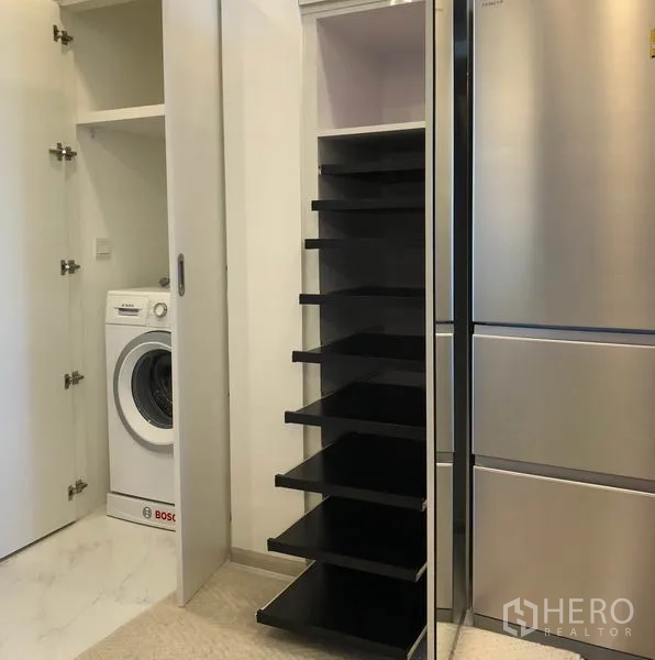 Condominium for rent in Bang Na, Bangkok - Utility area with a tall refrigerator, pull-out shelving and a Bosch washing machine.