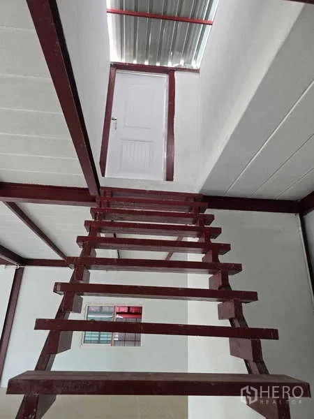 Warehouse for rent in Mueang Samut Sakhon, Samut Sakhon - Steep red metal staircase leading to an upper white door inside a warehouse.