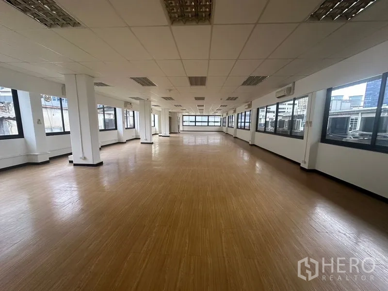 Office Space for rent in Bang Rak, Bangkok - Bright open office area featuring timber-style floors, ceiling lighting, and city-facing windows.