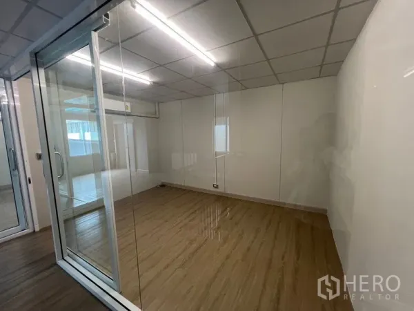 Warehouse for rent in Prawet, Bangkok - Glass-partitioned meeting room with wood-look flooring and ceiling lights.