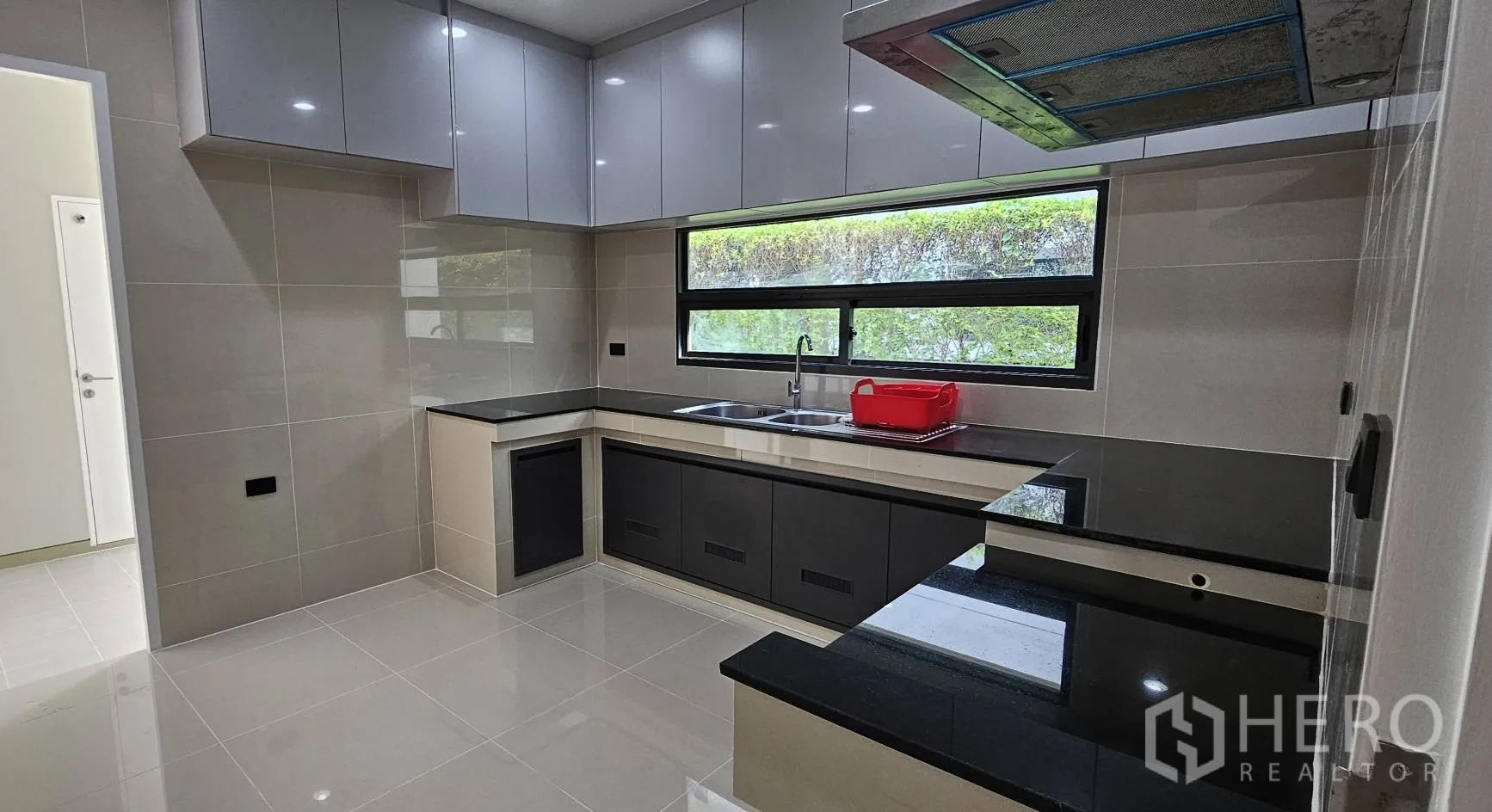 Detached House for rent in Bang Kapi, Bangkok - Modern U-shaped kitchen with black stone countertops and a long window.