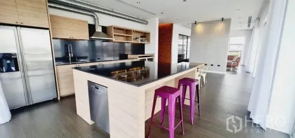 Condominium for rent in Watthana, Bangkok - Modern kitchen with black-stone island, stainless appliances and purple bar stools.