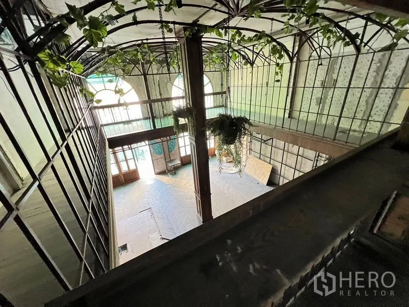 Shophouse for rent in Watthana, Bangkok - Upper view into a double-height space with glass and greenery accents.
